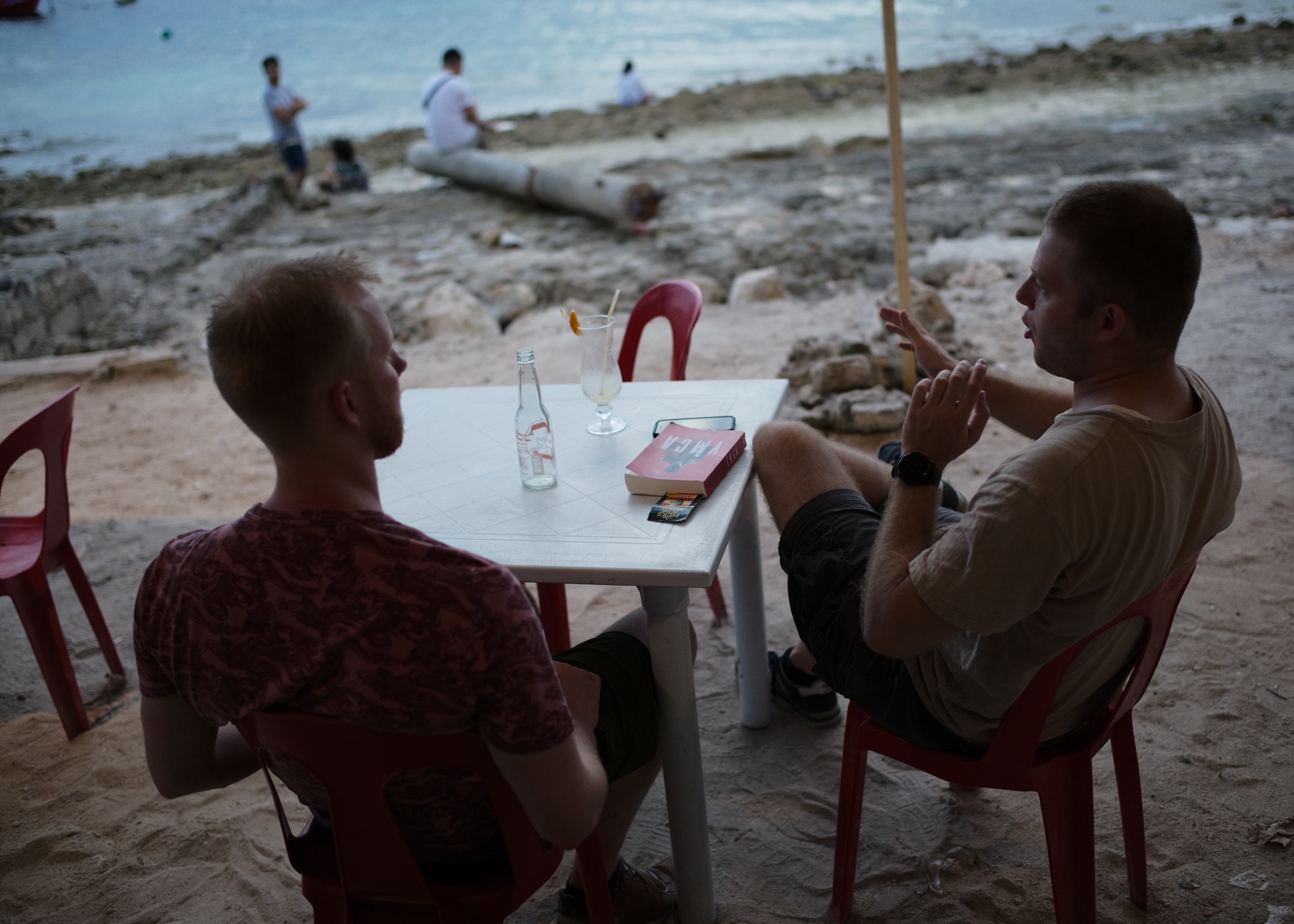 People talking at a table beside the beach
